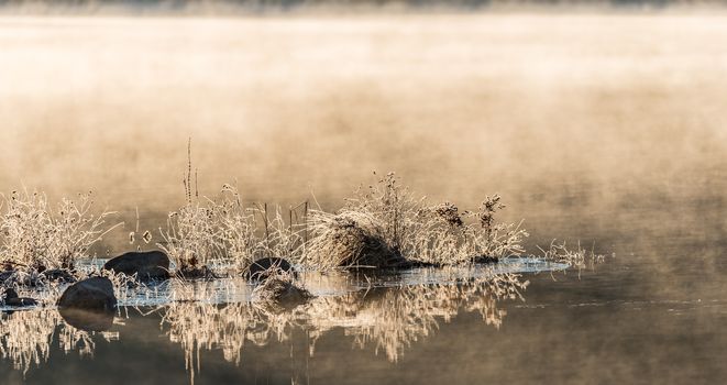 November waterfront, mist rising from warm lake water into chilled morning air.  lake with rising fog background.