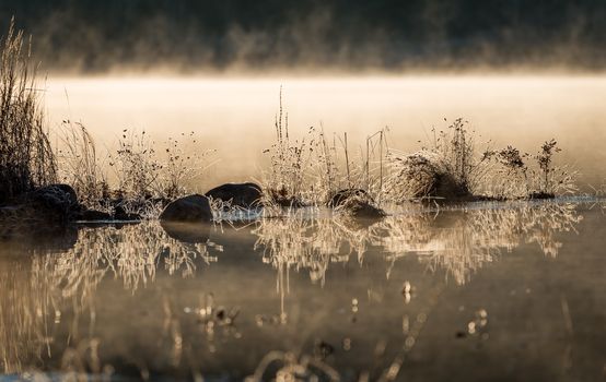 November waterfront, mist rising from warm lake water into chilled morning air.  lake with rising fog background.