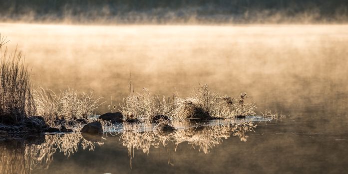 November waterfront, mist rising from warm lake water into chilled morning air.  lake with rising fog background.