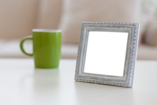 Close up detailed front view of white blank wooden frame with copy space, next to a mug.