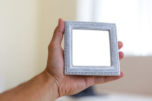 Close up detailed front view of white blank wooden frame with copy space, holding on man hand.