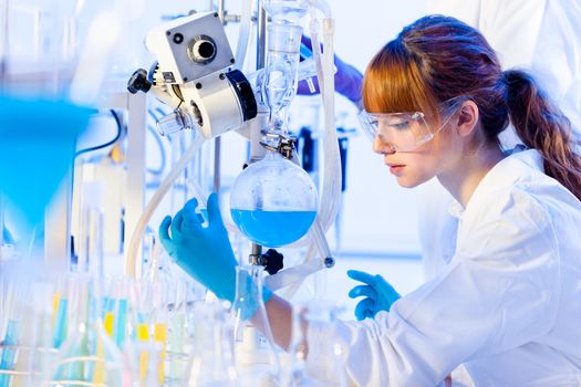 Life science laboratory. Attractive young PhD sscientist observing the blue indicator color shift after the solution  destillation.