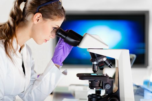 Life scientist researching in laboratory. Portrait of a attractive, young, confident female health care professional microscoping in hes working environment. Healthcare and biotechnology.