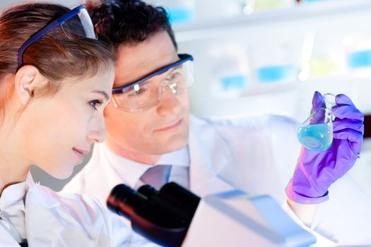 Life science laboratory. Attractive young PhD sscientist observing the blue indicator color shift after the solution  destillation.