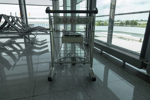 An isolated luggage transporter and some seats in an airport