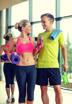 sport, fitness, lifestyle and people concept - smiling couple with water bottles in gym