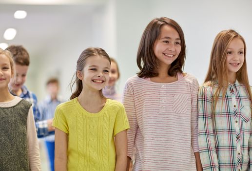 education, elementary school, drinks, children and people concept - group of smiling school kids walking in corridor