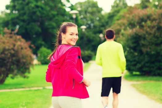 fitness, sport, friendship and lifestyle concept - smiling couple running outdoors