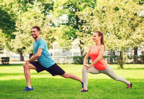 fitness, sport, training and lifestyle concept - smiling couple stretching outdoors