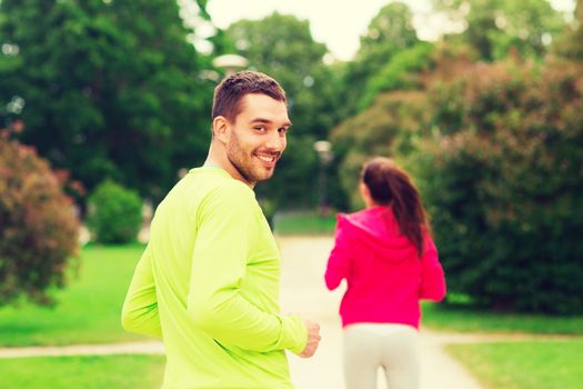 fitness, sport, friendship and lifestyle concept - smiling couple running outdoors