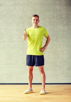 sport, fitness, lifestyle and people concept - smiling man showing thumbs up in gym
