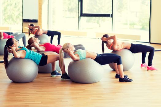 fitness, sport, training and lifestyle concept - group of smiling women with exercise balls in gym