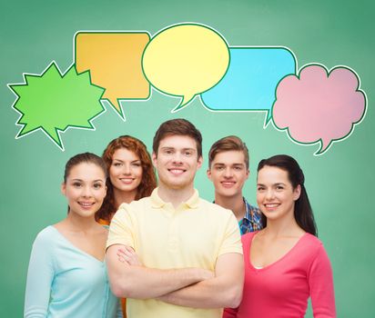 school, education, communication and people concept - group of smiling teenagers over green board background with text bubbles