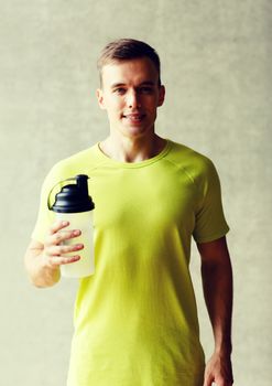 sport, fitness, lifestyle and people concept - smiling man with protein shake bottle in gym