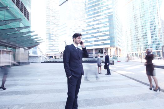 Handsome businessman talking on the cellphone outside office building