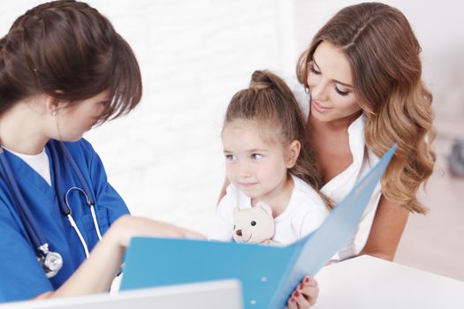 Young pediatrician doctor talking with girl and her mother