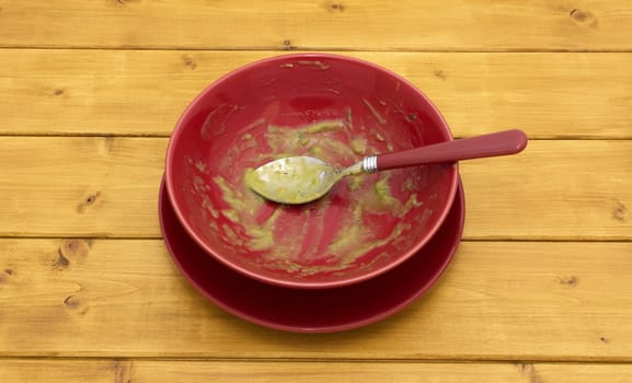 Empty soup bowl with remainder of green pea and ham soup on a wooden kitchen table