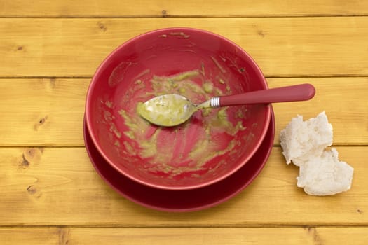 Pieces of white bread on table next to an emptied bowl of pea and ham soup