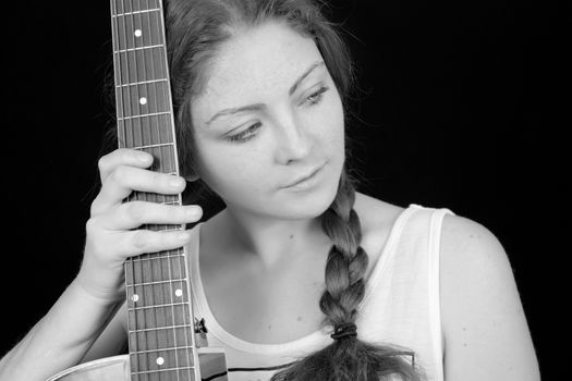 Beautiful woman with a guitar on a black background