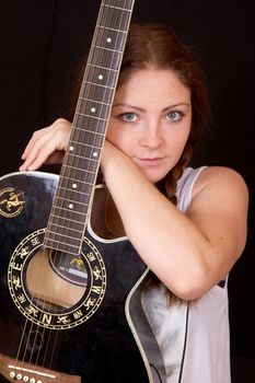 Beautiful woman with a guitar on a black background