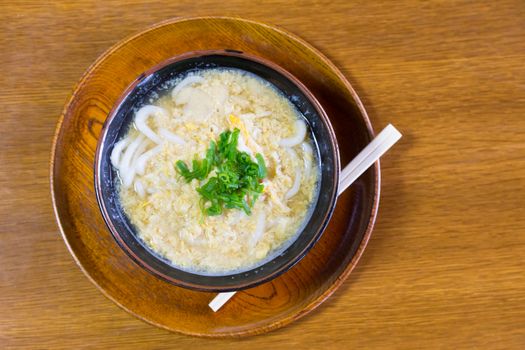 Miso Ramen Asian noodles with egg and parsley in wooden bowl on brown rustic background.