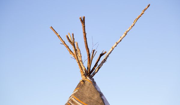 Top of a Tipi with a clear blue sky behind it.