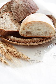 Farm still life. Freshness bread set on white tablecloth near wheat ears