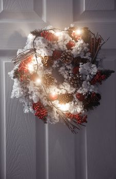 Christmas wreath and light on a white front door