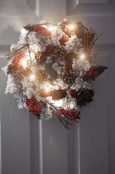 Christmas wreath and light on a white front door