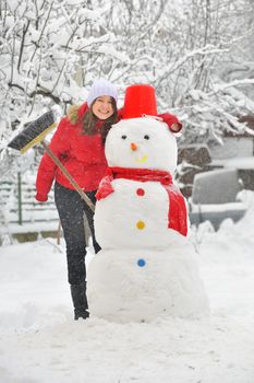 happy girl making a snowman in garden