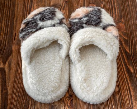 Home slippers made of sheep wool on a wooden background