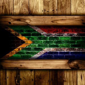 Abstract background of a South African flag on a brick wall framed by wooden panels.