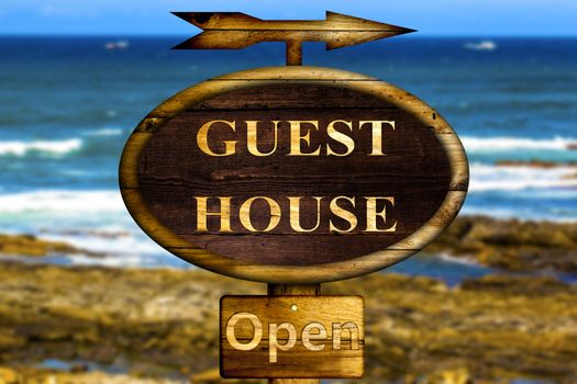 Wooden Guest house sign with a ocean background.
