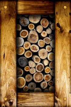 Abstract image of dry cut firewood logs in a pile inside a wooden frame.
