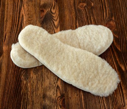 insole of sheepskin on a brown wooden background