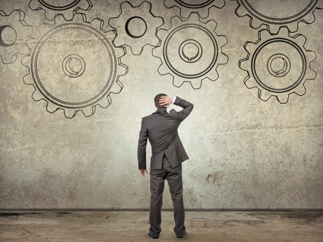 Businessman looking at cog wheels on abstract background