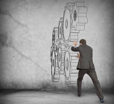 Businessman pushing cog wheel on abstract background