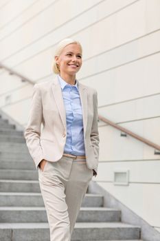 business, people and education concept - young smiling businesswoman walking down stairs outdoors