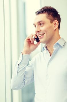 business, technology and office concept - smiling businessman with smartphone in office