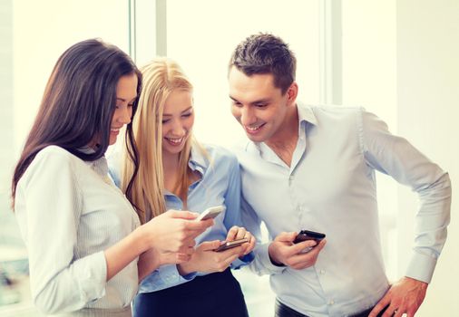 business and technology concept - smiling business team with smartphones in office