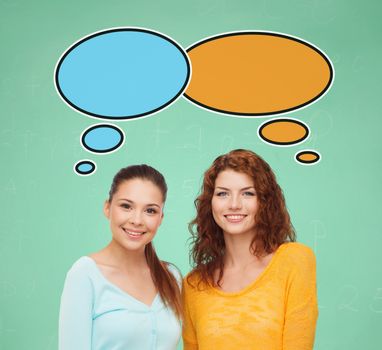 school, education, communication and people concept - smiling student girls over green board background with text bubbles
