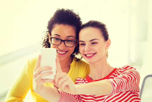 education, leisure and technology concept - two girlfriends taking selfie with smartphone camera