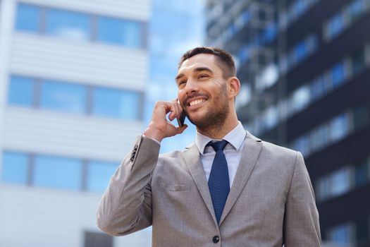 business, technology and people concept - smiling businessman with smartphone talking over office building