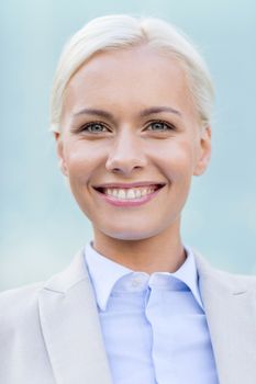 business, people and education concept - young smiling businesswoman over office building