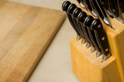Block holding a bunch of knives with a cutting board on teh counter