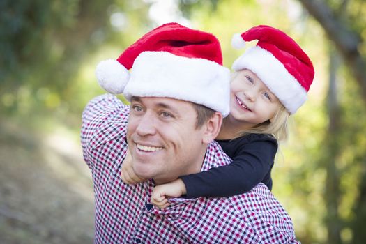 Happy Father and Daughter Having Fun Wearing Santa Hats Outdoors.