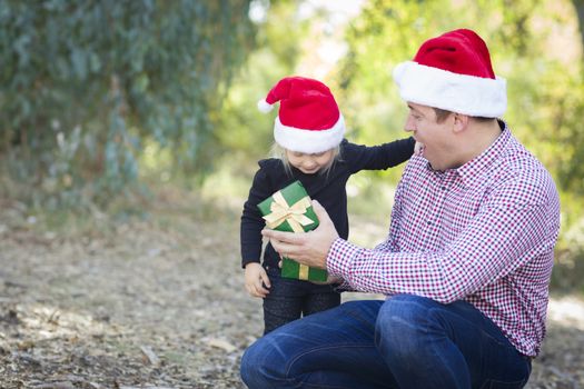 Happy Father Giving Young Daughter A Christmas Gift Outdoors.