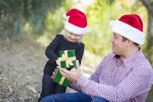 Happy Father Giving Young Daughter A Christmas Gift Outdoors.