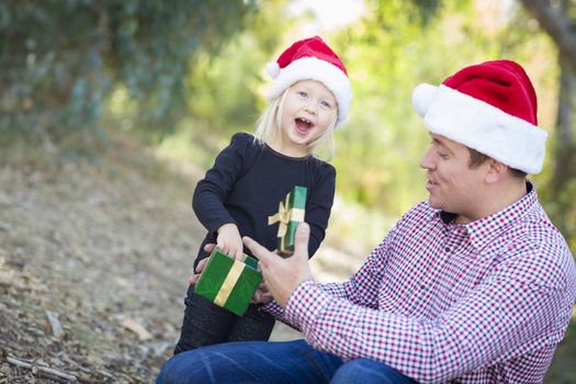 Happy Father Giving Young Daughter A Christmas Gift Outdoors.