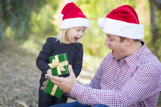 Happy Father Giving Young Daughter A Christmas Gift Outdoors.